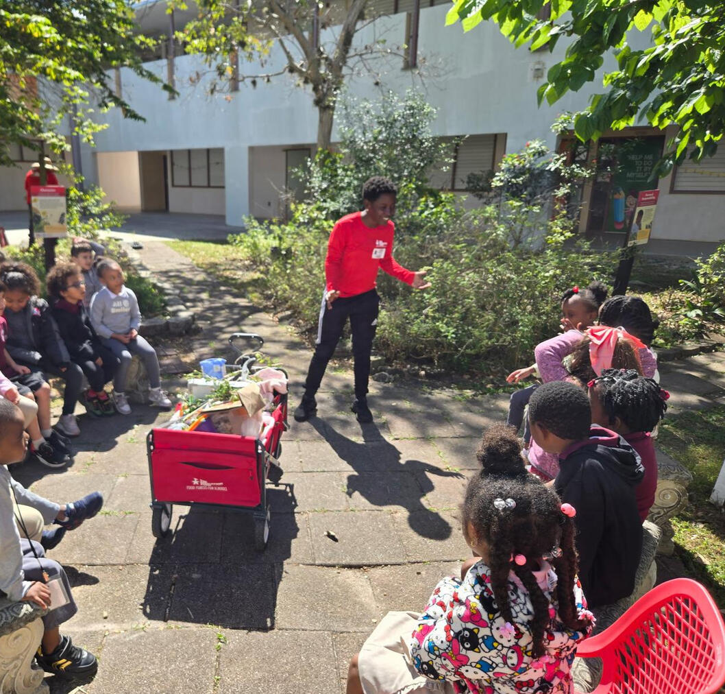 Taina teaching elementary school students a science lesson with plants. 2025